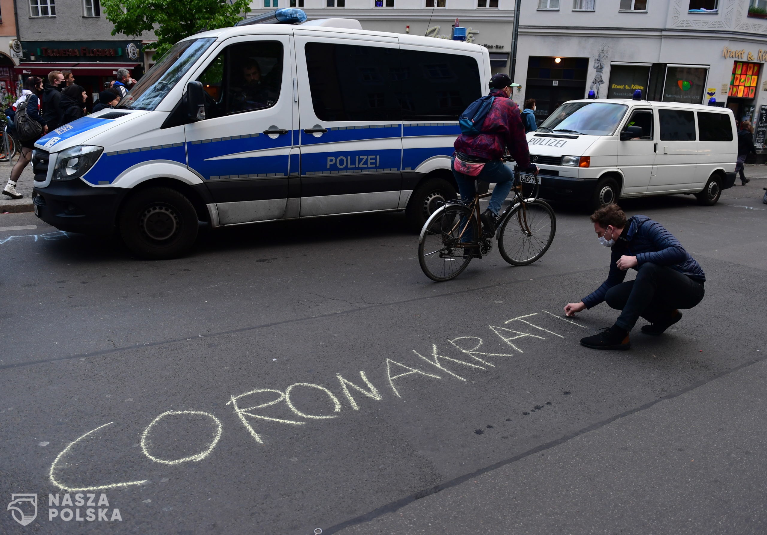 epa08396696 A man writes 'Coronacracy' on a street during a protest on May Day in the district Kreuzberg in Berlin, Germany, 01 May 2020. Labour Day, or May Day, is observed all over the world on the first day of May to celebrate the economic and social achievements of workers and fight for labourers rights. This year, May Day takes place under the influence of the pandemic crisis of the SARS-CoV-2 coronavirus which causes the Covid-19 disease.  EPA/FILIP SINGER 
Dostawca: PAP/EPA.