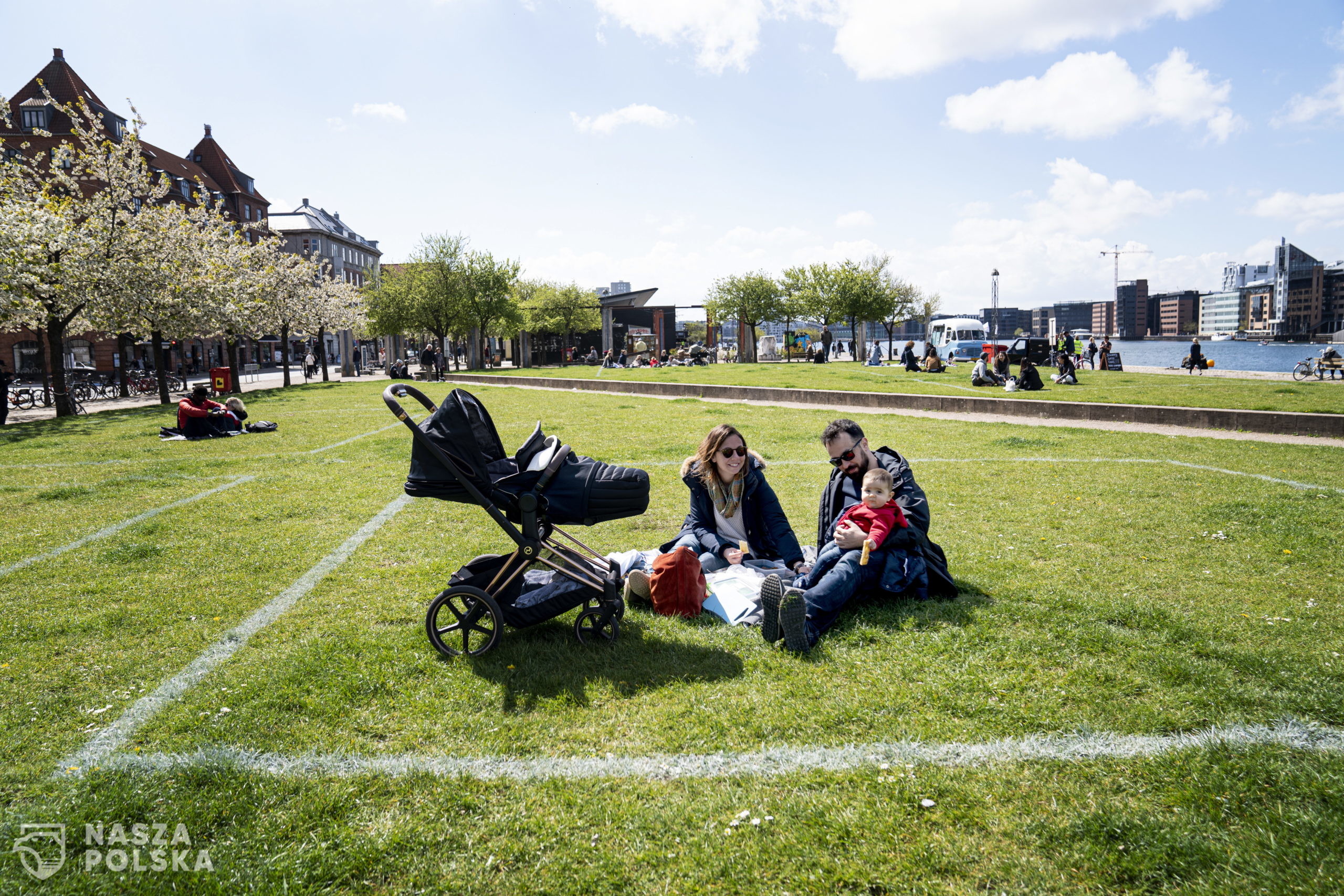 epa08398885 Marina and Andrea enjoy the sun with their daughter Sara at Islands Brygge in Copenhagen, Denmark, 03 May 2020. Marked areas of 40 m2 in which only 10 people can stay, will help citizens keep distance to prevent the spread of SARS-CoV-2 coronavirus which causes the Covid-19 disease. The green area is a favorite place of leisure activities for the residents of Islands Brygge.  EPA/IDA GULDBAEK ARENTSEN  DENMARK OUT  ** NOTE the picture taken with a telephoto lens and the distance between people in the picture can be perceived less than it really is. ** 
Dostawca: PAP/EPA.