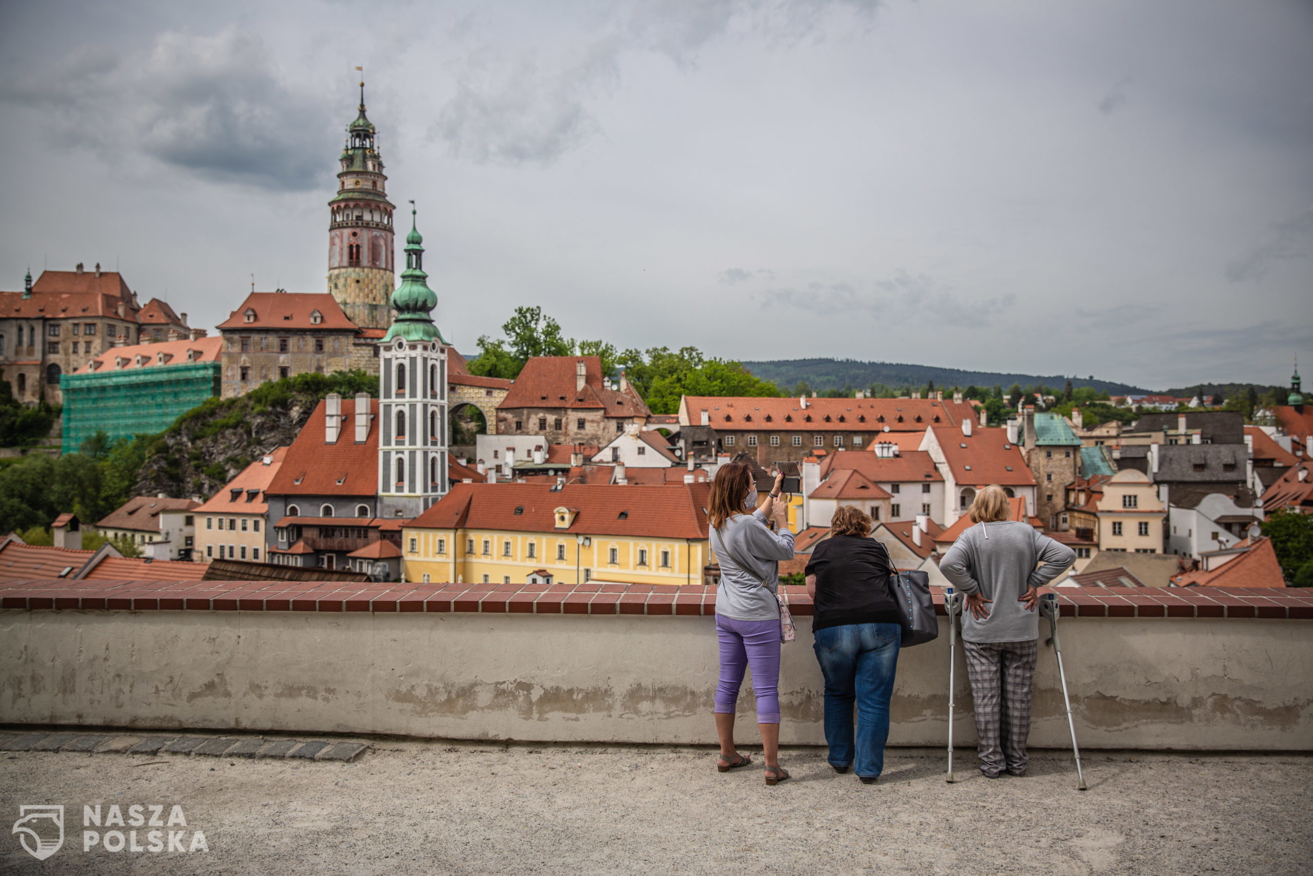 epa08438219 People look down at almost empty vantage point above the old town of Cesky Krumlov, UNESCO World Culture Heritage site, Czech Republic, 22 May 2020. According to local media, more than 15.000 tourists from Asia arrived in the South Bohemian region, where is located the popular tourist destination Cesky Krumlov, on January 2020. Due to the pandemic COVID-19 disease caused by the SARS-CoV-2 coronavirus, which closed borders and restricted travel, the number of accommodated tourists in southern Bohemia fell by 30 percent in the first quarter. The region is the most affected in the country.  EPA/MARTIN DIVISEK 
Dostawca: PAP/EPA.