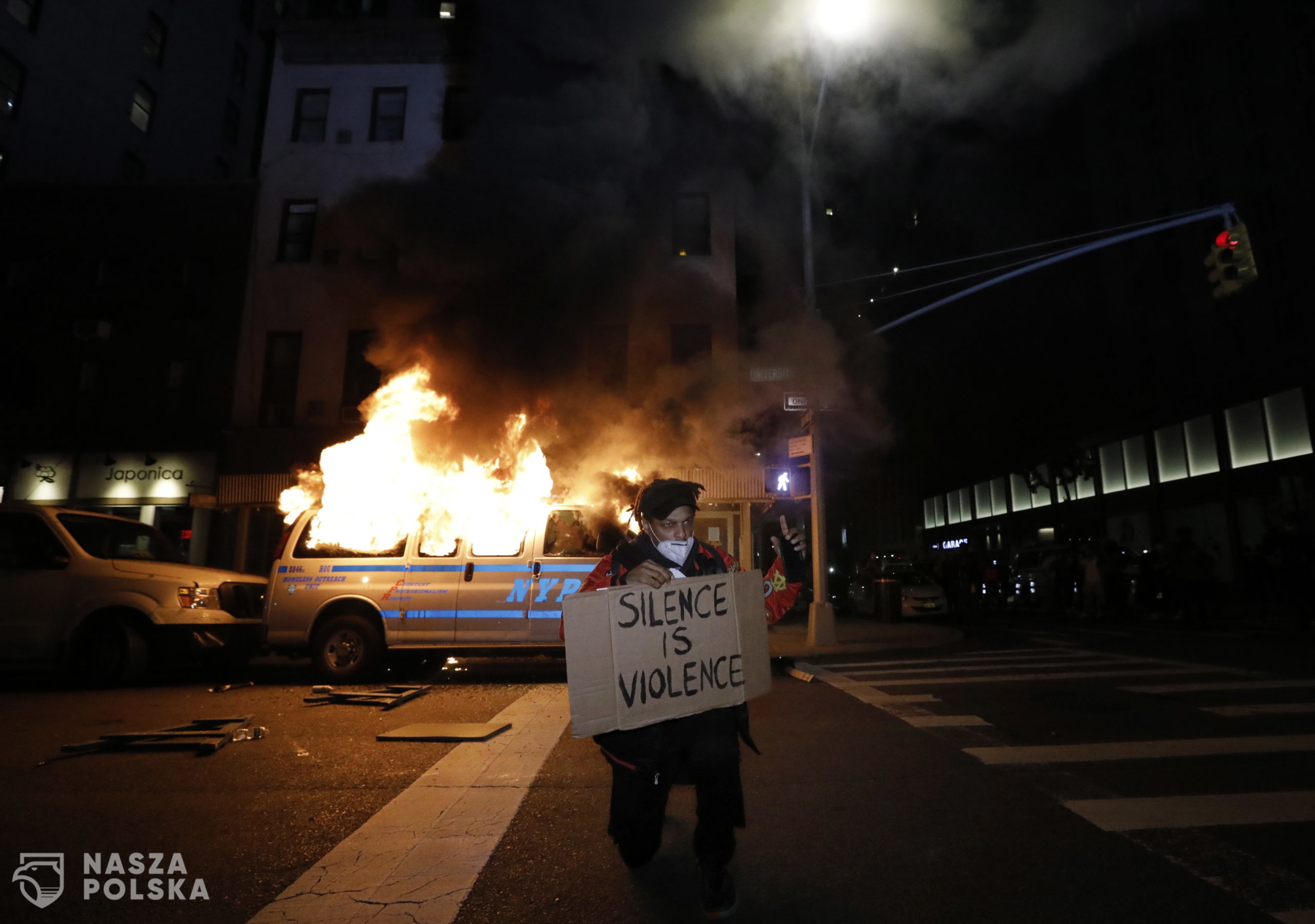 epa08455442 A demonstrator kneels in front of a police van burning during protests over the Minneapolis arrest of George Floyd, who later died in police custody, at Union Square, New York, USA, 30 May 2020. A bystander's video posted online on 25 May, appeared to show George Floyd, 46, pleading with arresting officers that he couldn't breathe as an officer knelt on his neck. The unarmed Black man later died in police custody. On 29 May, Derek Chauvin, the police officer in the center of the incident has been taken into custody and charged with murder in the Floyd arrest.  EPA/PETER FOLEY 
Dostawca: PAP/EPA.