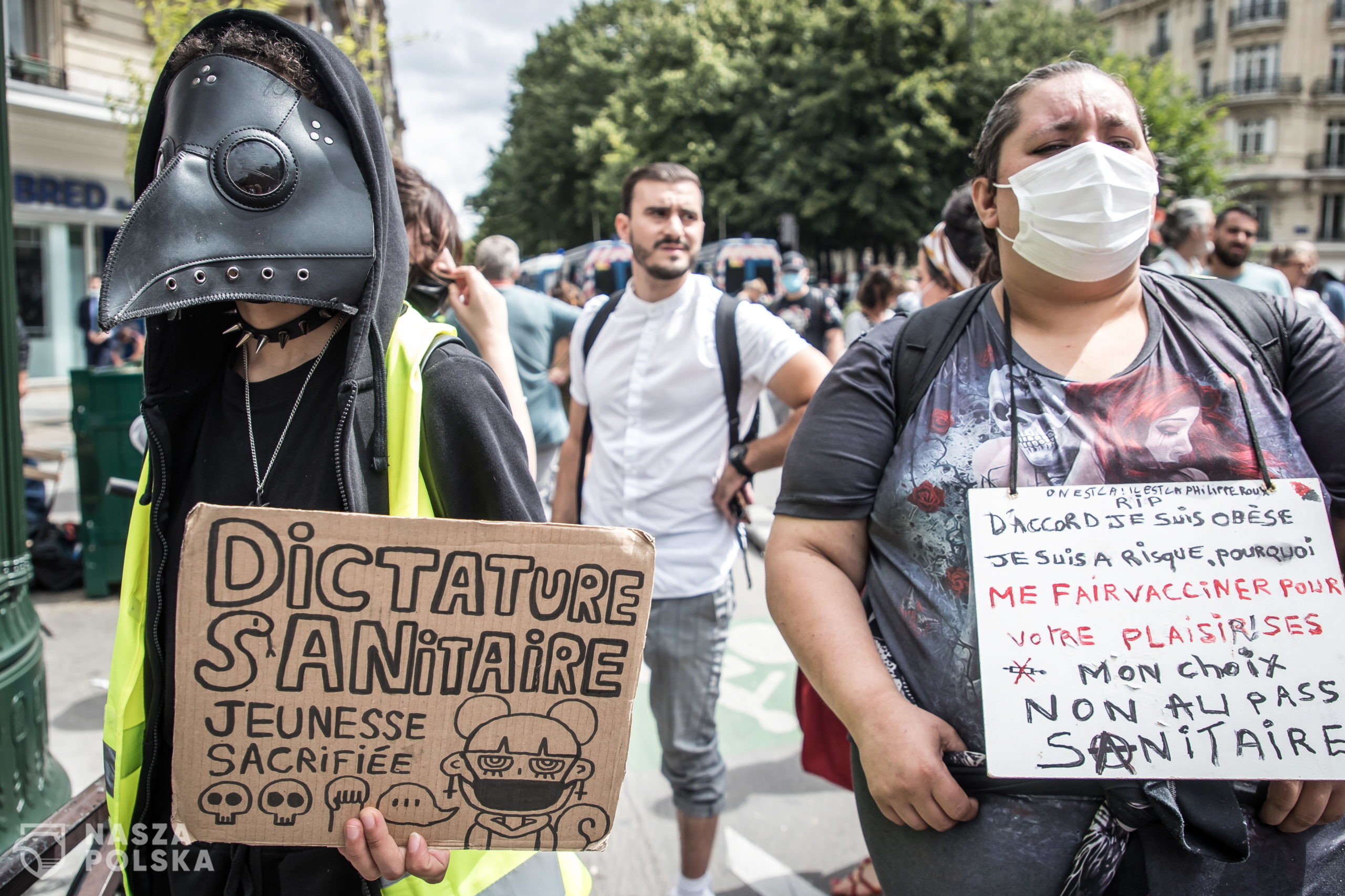 epa09382550 A protester holds a poster reading 'Sanitary Dictature, Youngness sacrified' during a demonstration against the COVID-19 health pass which grants vaccinated individuals greater ease of access to venues in France, in Paris, France, 31 July 2021. Anti-vaxxers, joined by the anti-government 'yellow vest' movement, are demonstrating across France for the third consecutive week in objection to the health pass, which is now mandatory for people to  visit leisure and cultural venues.  EPA/CHRISTOPHE PETIT TESSON 
Dostawca: PAP/EPA.