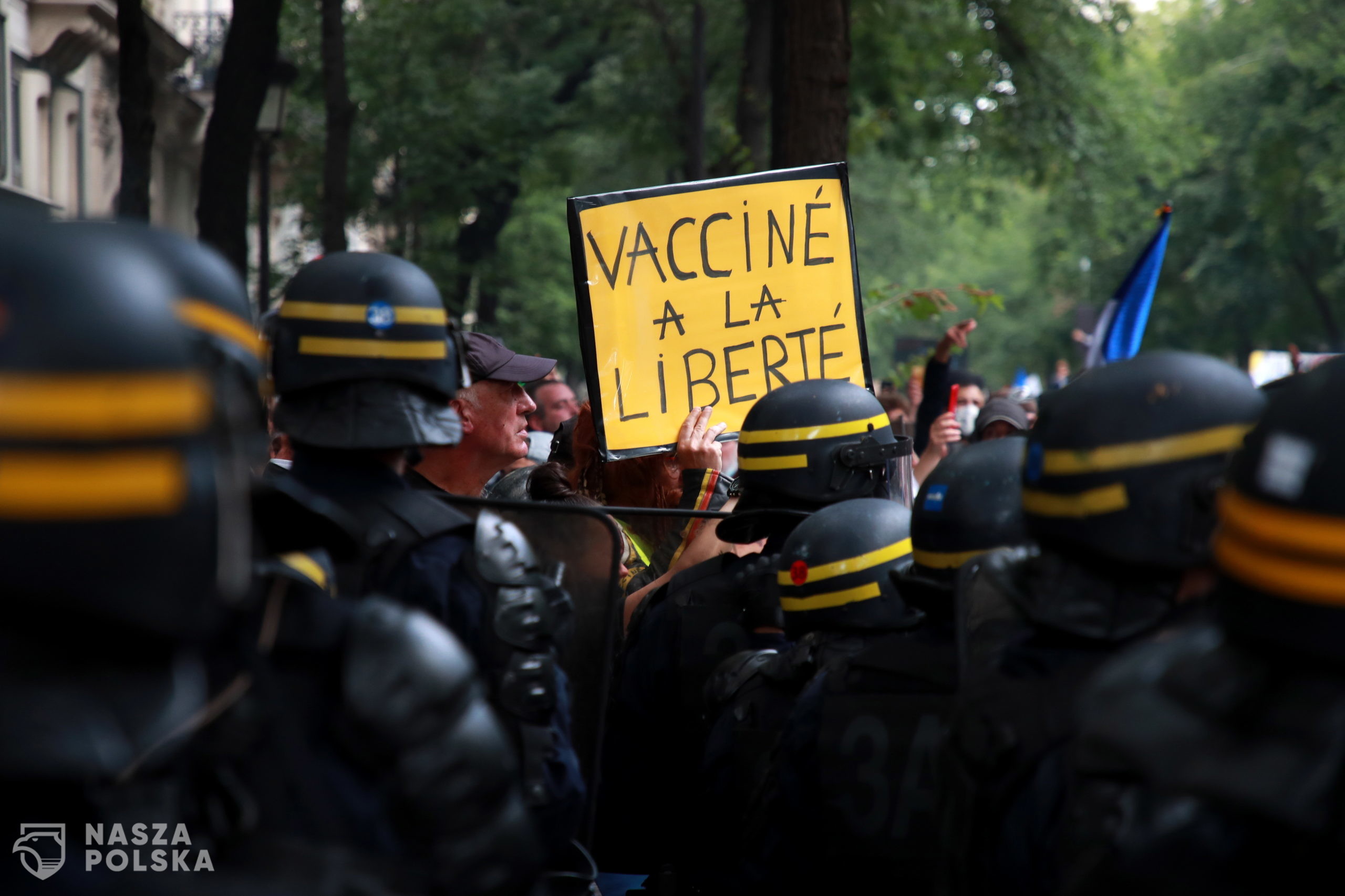 epa09383069 A protester holds a poster reading 'Vaccinated with freedom' during a demonstration against the COVID-19 health pass which grants vaccinated individuals greater ease of access to venues in France, in Paris, France, 31 July 2021. Anti-vaxxers, joined by the anti-government 'yellow vest' movement, are demonstrating across France for the third consecutive week in objection to the health pass, which is now mandatory for people to  visit leisure and cultural venues.  EPA/CHRISTOPHE PETIT TESSON 
Dostawca: PAP/EPA.