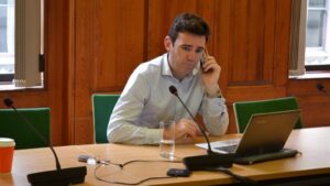 Andy Burnham, katolik na czele brytyjskiego rządu, przy stole konferencyjnym z telefonem przy uchu