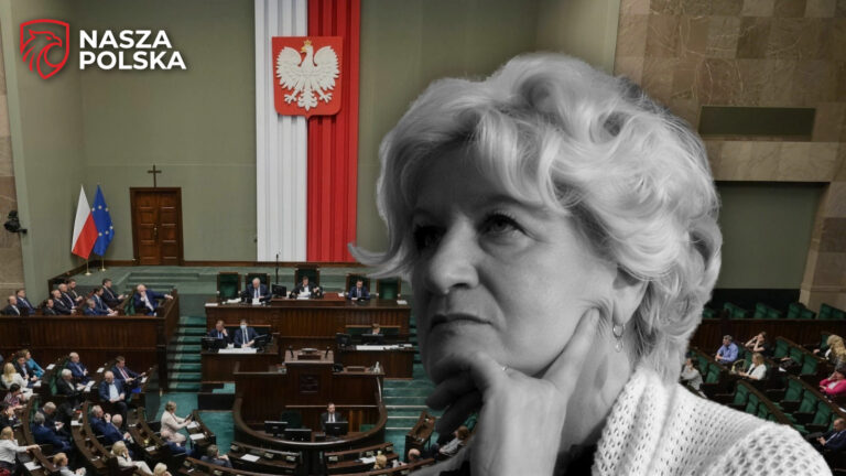 Elżbieta Baryś w ujęciu portretowym po prawej stronie kadru, w tle sala plenarna Sejmu z godłem