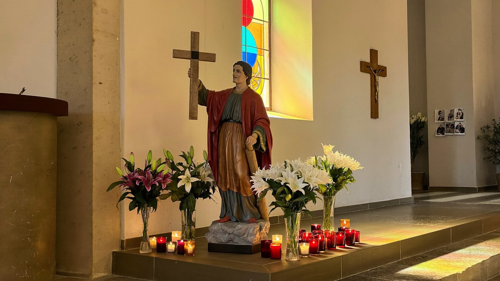 Figura świętego Józefa w kaplicy wśród zapalonych świec i lilii