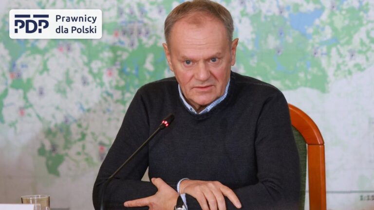 Premier Donald Tusk przy mikrofonie na tle mapy, obok logo stowarzyszenia Prawnicy dla Polski