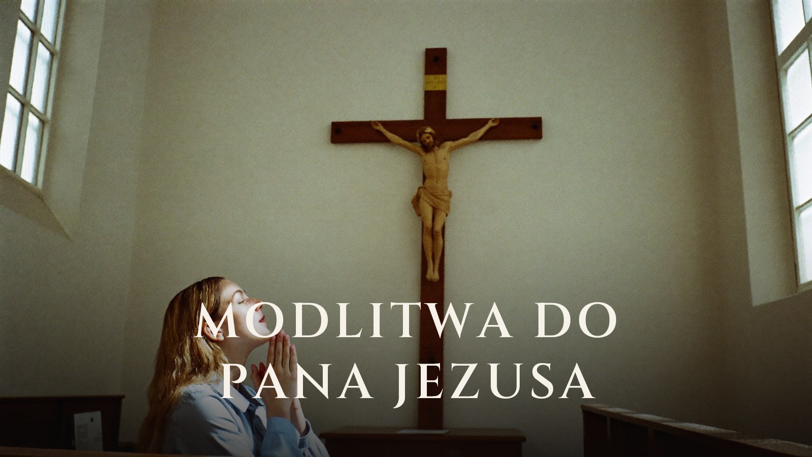 Młoda kobieta klęczy ze złożonymi dłońmi przed dużym krucyfiksem w jasnym kościele