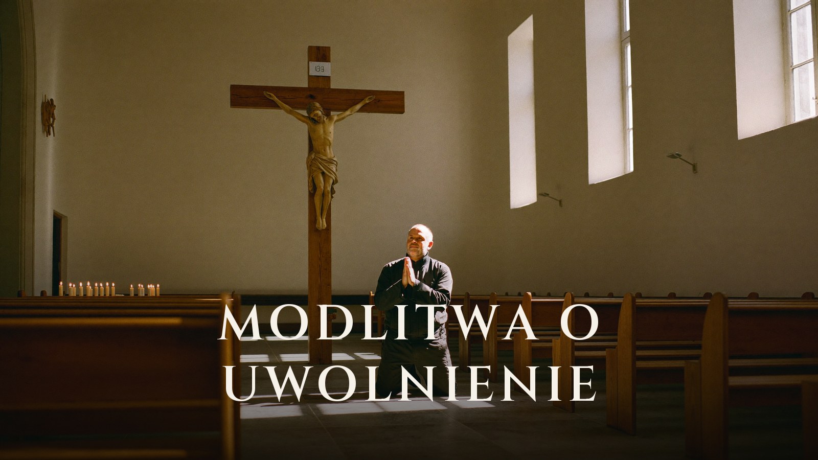 Mężczyzna modli się w kościele przed krzyżem