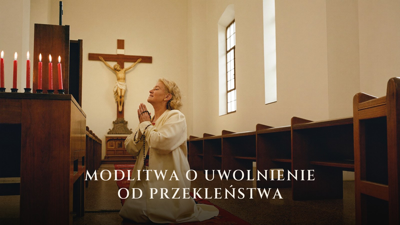 Kobieta z różańcem modli się w kościele przed krzyżem