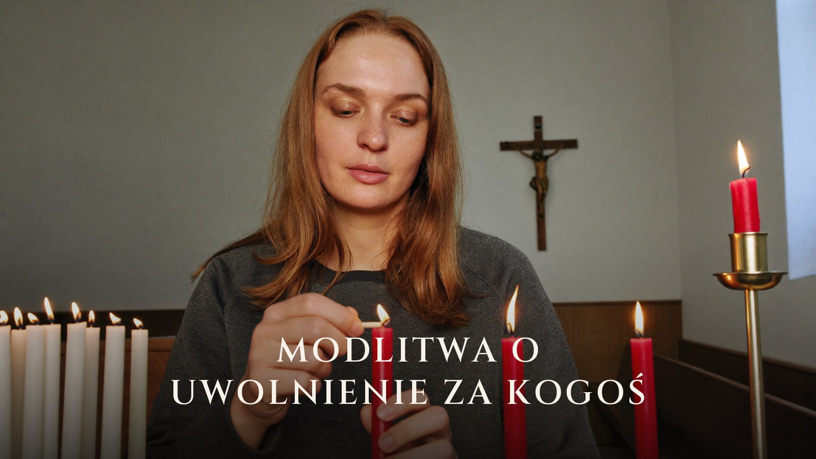 Kobieta zapala świecę w intencji drugiej osoby, na ścianie kościoła widoczny krucyfiks