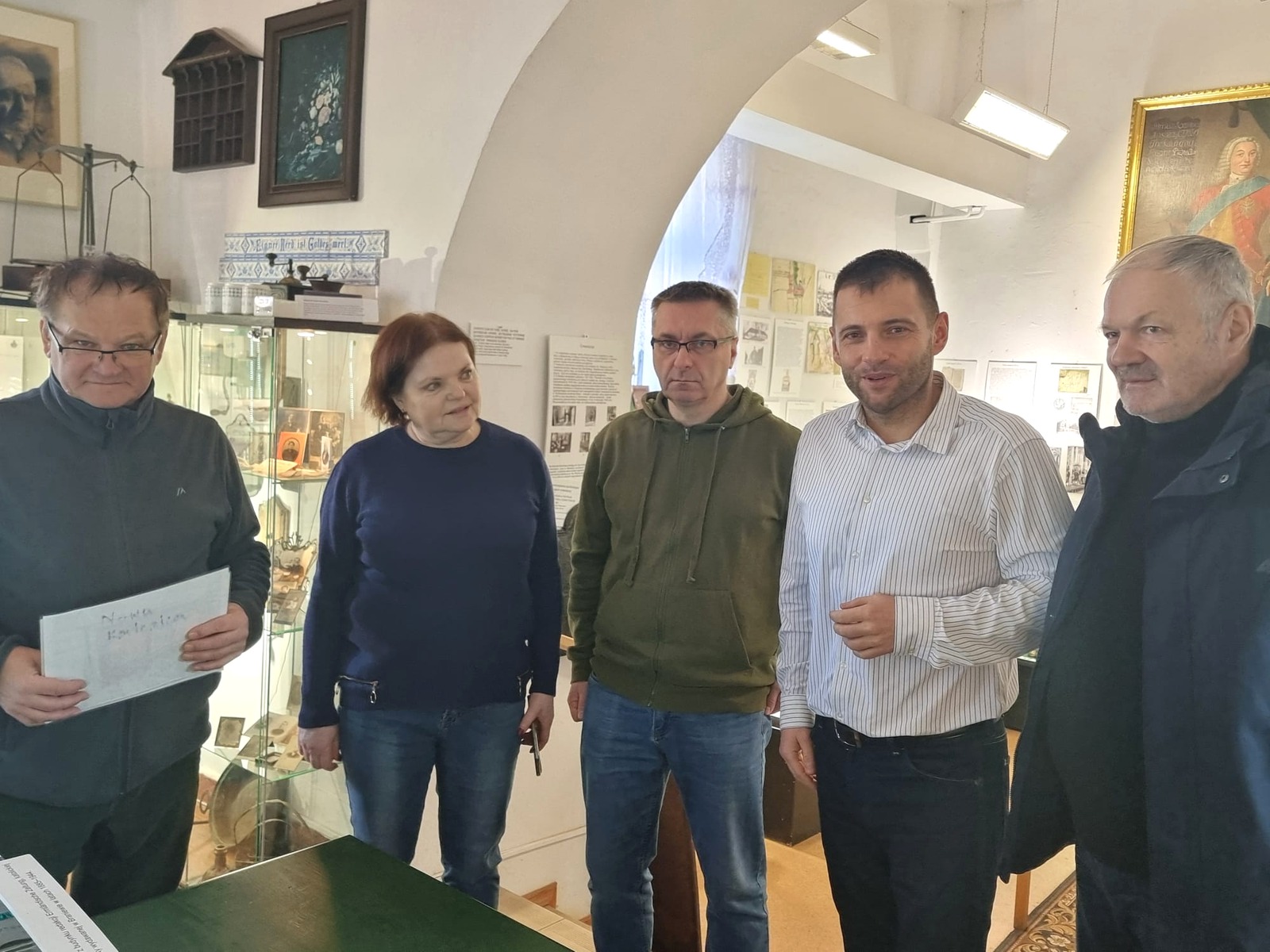 Uczestnicy przekazania tłoka pieczętnego stoją przy gablotach w sali wystawowej Muzeum Ziemi Braniewskiej
