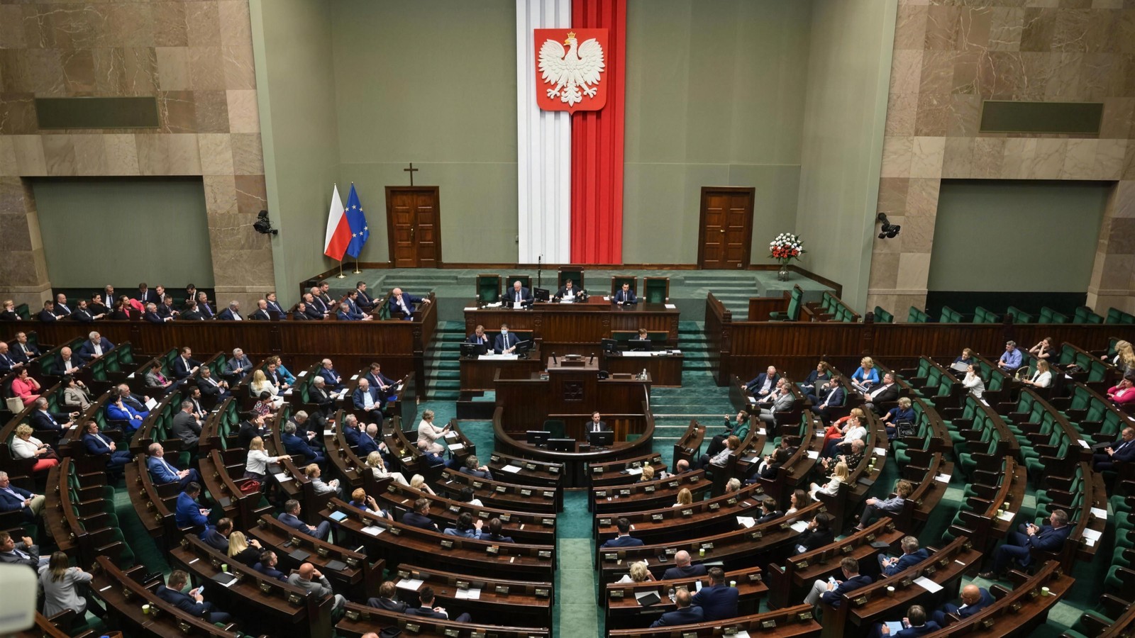 Sala plenarna Sejmu Rzeczypospolitej Polskiej podczas obrad, posłowie w ławach i pusta mównica