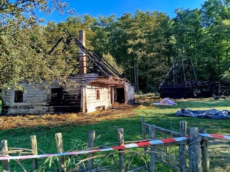 Spalona drewniana chałupa i zwęglone konstrukcje na terenie sanockiego skansenu po nocnym pożarze
