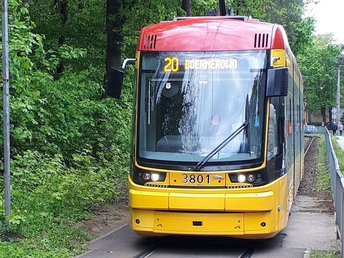 Tramwaj 20 Boernerowo z tablicą kierunkową wjeżdża na jednotorowy odcinek wśród drzew