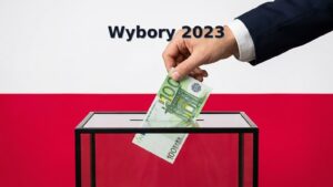 Dłoń w garniturze wsuwa banknot 100 euro do szklanej urny wyborczej na tle polskiej flagi