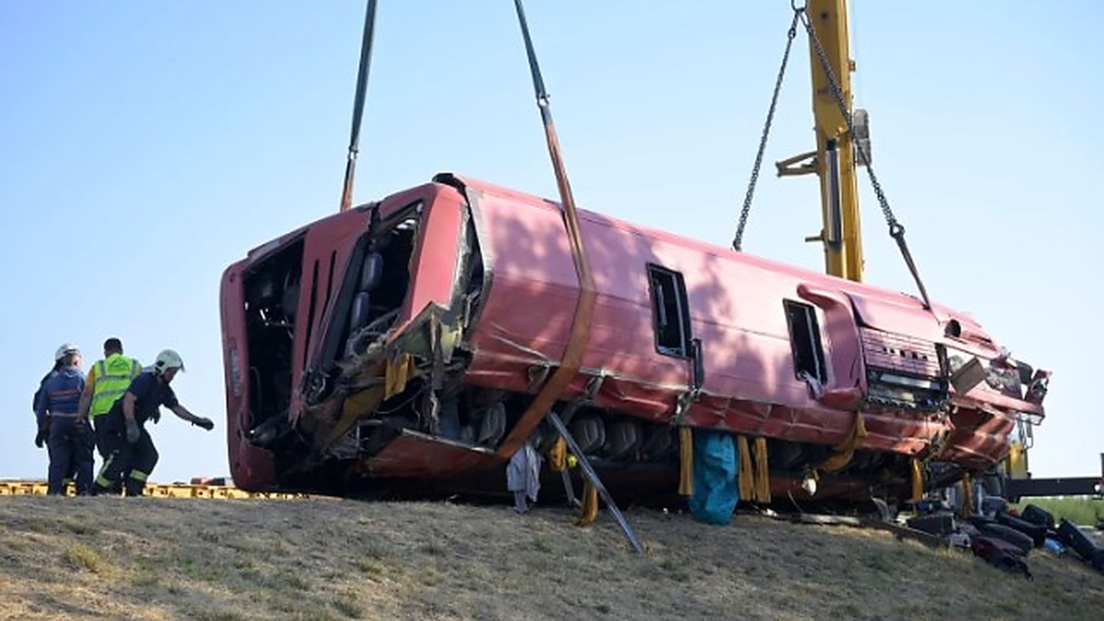Przewrócony polski autokar podnoszony dźwigiem przy autostradzie M3 na Węgrzech, obok pracują strażacy
