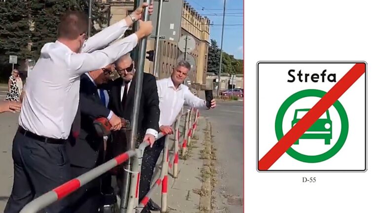 Mężczyźni w białych koszulach wyjmują słupek ze znakiem Strefy Czystego Transportu przy krakowskiej ulicy