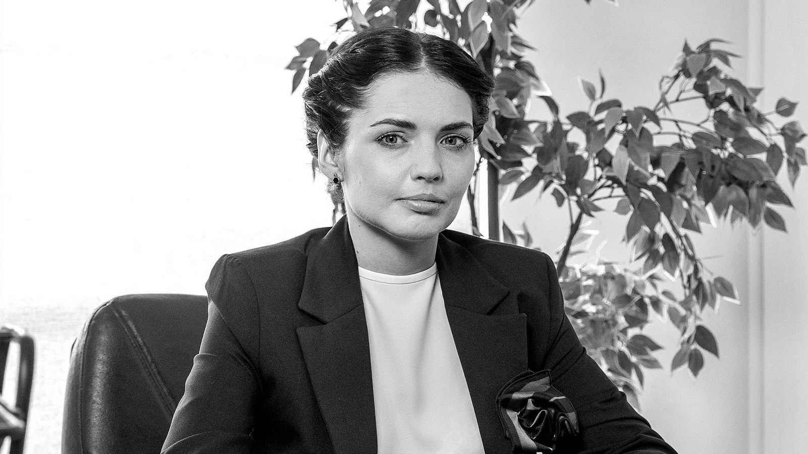 Katarzyna Zaczek w czarnej marynarce siedzi przy biurku, zdjęcie czarno-białe