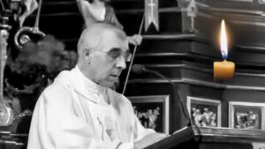Ksiądz Stanisław Zbojnowicz w albie przy ambonie w kościele, obok pali się świeca, kadr czarno-biały