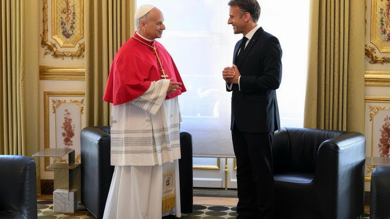 Leon XIV w czerwonej pelerynie rozmawia z uśmiechniętym Emmanuelem Macronem w złoconym salonie Pałacu Elizejskiego