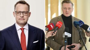 Marcin Romanowski w garniturze i czerwonym krawacie obok mec. Bartosza Lewandowskiego mówiącego do mikrofonów