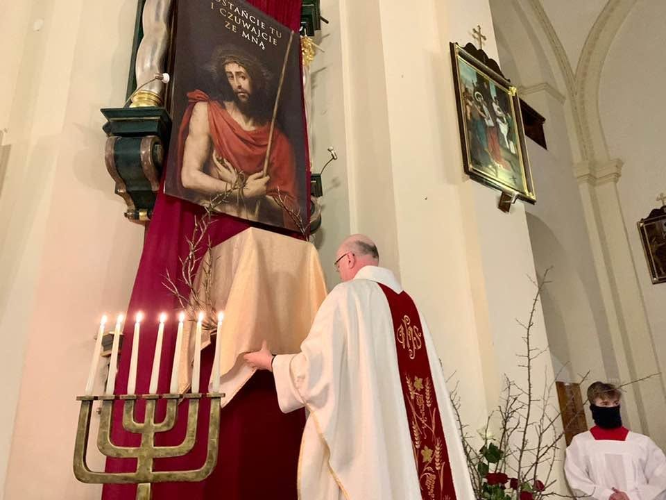 Kapłan w białym ornacie odsłania obraz Chrystusa w cierniowej koronie z napisem Zostańcie tu i czuwajcie ze mną