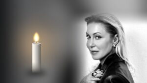 Monika Koszewska, czarno-biały portret obok zapalonej świecy na ciemnym tle