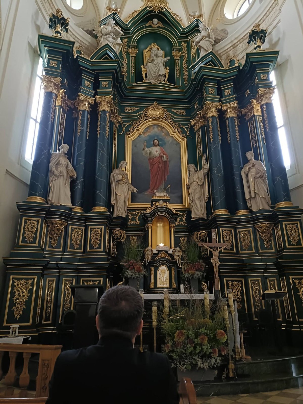 Wierny modli się przed zielono-złotym barokowym ołtarzem z obrazem Serca Jezusowego w Jarosławskim Opactwie