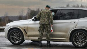 Żołnierz w mundurze polowym i berecie z lizakiem w dłoni przy srebrnym SUV-ie, świadczenia rzeczowe na rzecz obrony