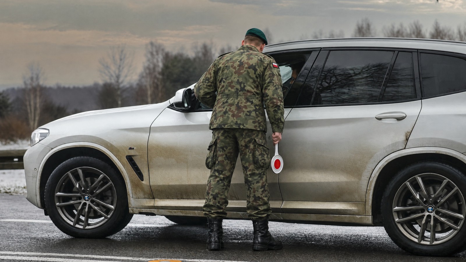 Żołnierz w mundurze polowym i berecie z lizakiem w dłoni przy srebrnym SUV-ie, świadczenia rzeczowe na rzecz obrony