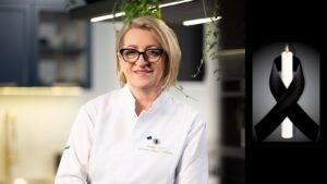Arleta Żynel w białej bluzie kucharskiej w studyjnej kuchni, obok świeca z czarną wstążką