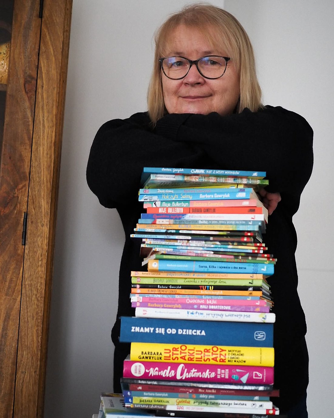 Barbara Gawryluk obejmuje wysoki stos napisanych i przetłumaczonych przez siebie książek