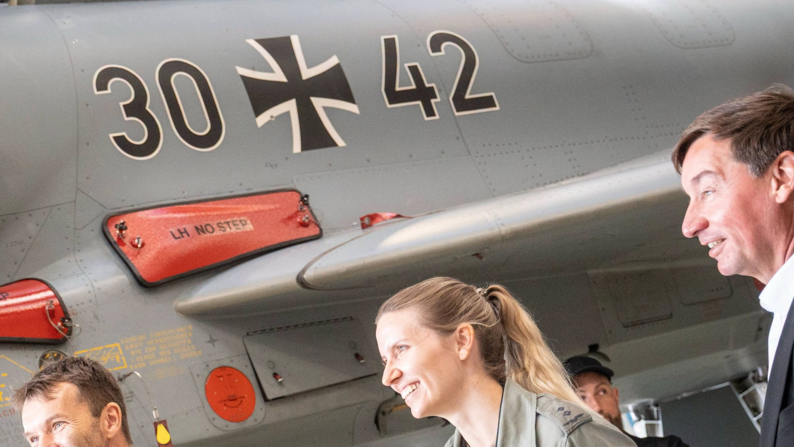 Uśmiechnięci piloci Luftwaffe w kombinezonach lotniczych stoją pod myśliwcem Eurofighter z oznaczeniem 30+42
