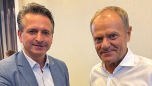 Poseł KO Robert Wardzała w niebieskiej marynarce obok premiera Donalda Tuska w białej koszuli