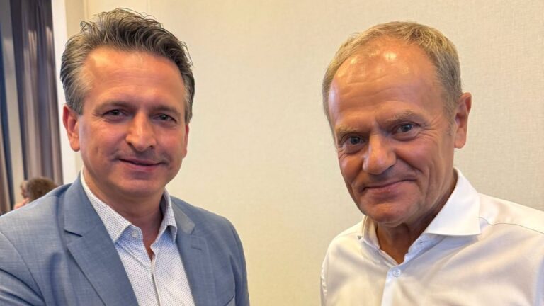 Poseł KO Robert Wardzała w niebieskiej marynarce obok premiera Donalda Tuska w białej koszuli