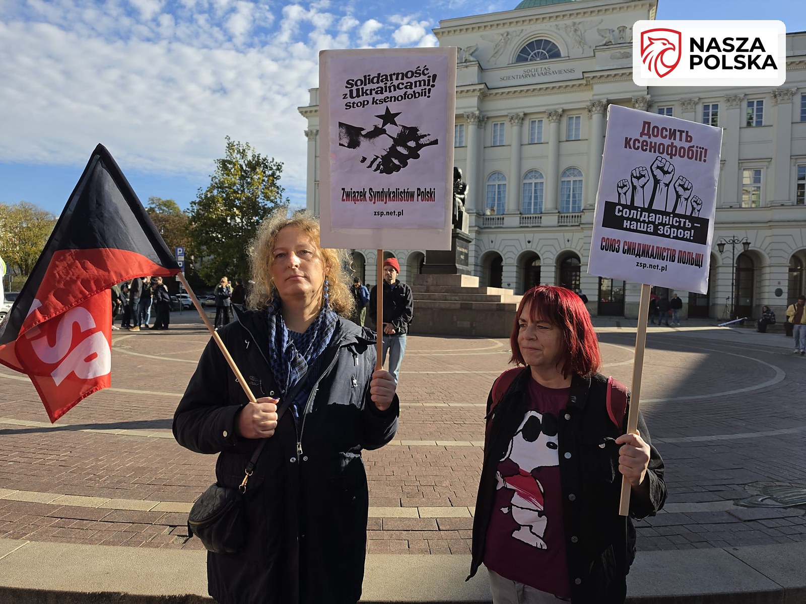 Uczestniczki manifestacji z transparentami Solidarność z Ukraińcami i flagą anarchosyndykalistów