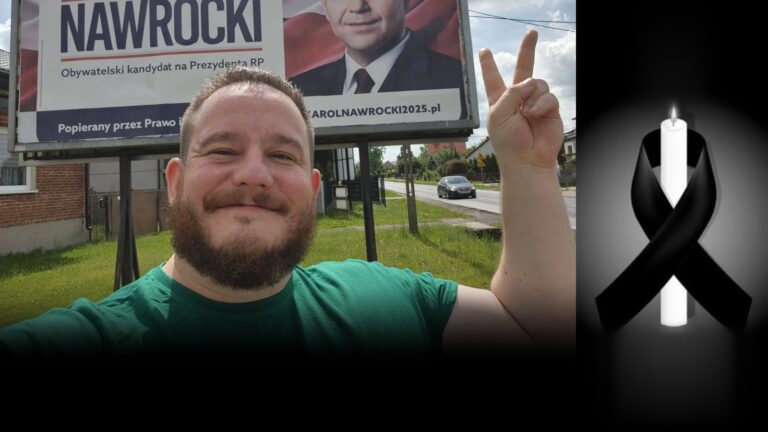Uśmiechnięty Waldemar Krysiak w zielonej koszulce pokazuje znak zwycięstwa, obok świeca z czarną wstążką
